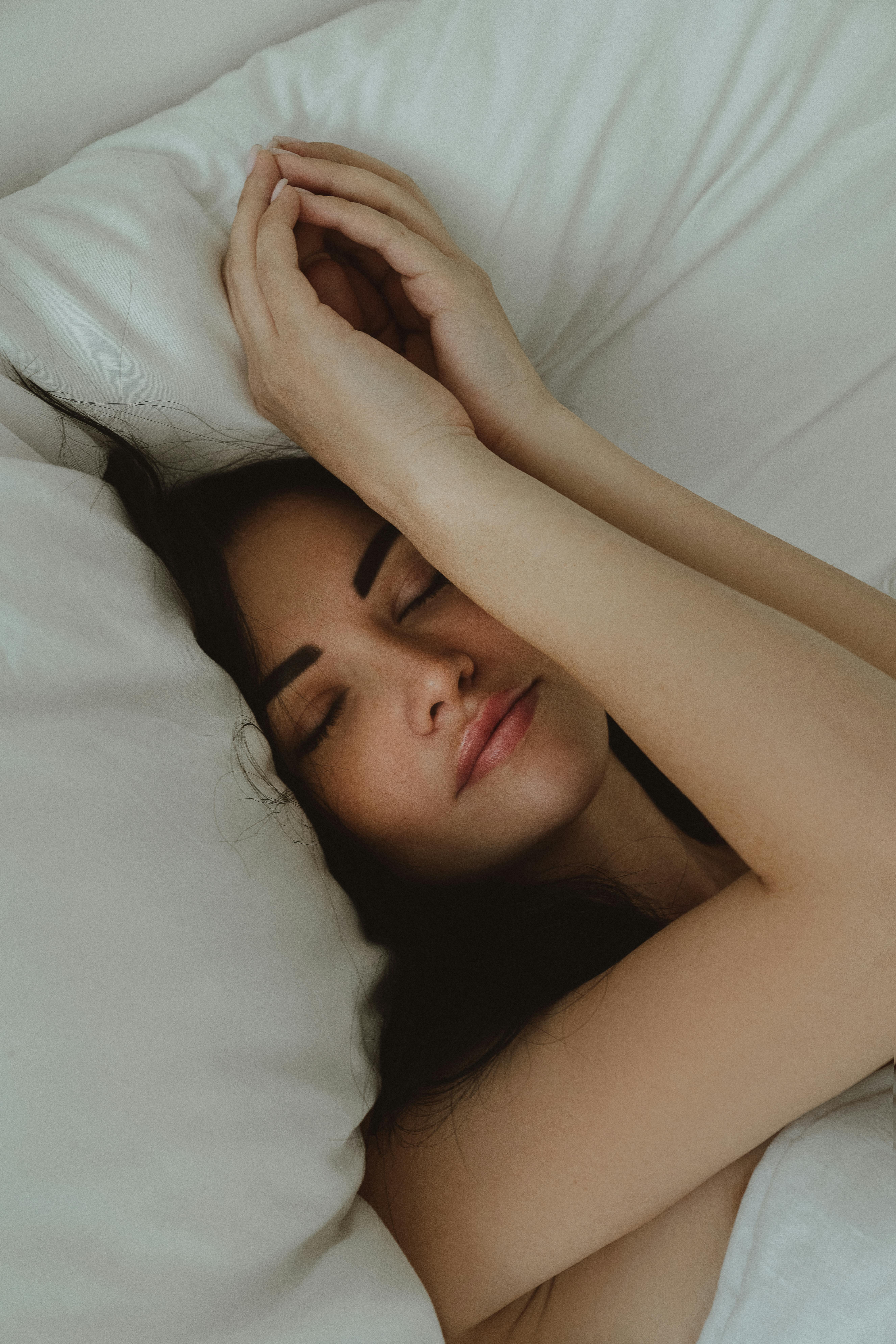 Restorative Sleep with Magnesium Glycinate | Calmly Rooted A woman sleeping peacefully on white linens, illustrating the restorative rest benefits of Magnesium Glycinate for sleep.