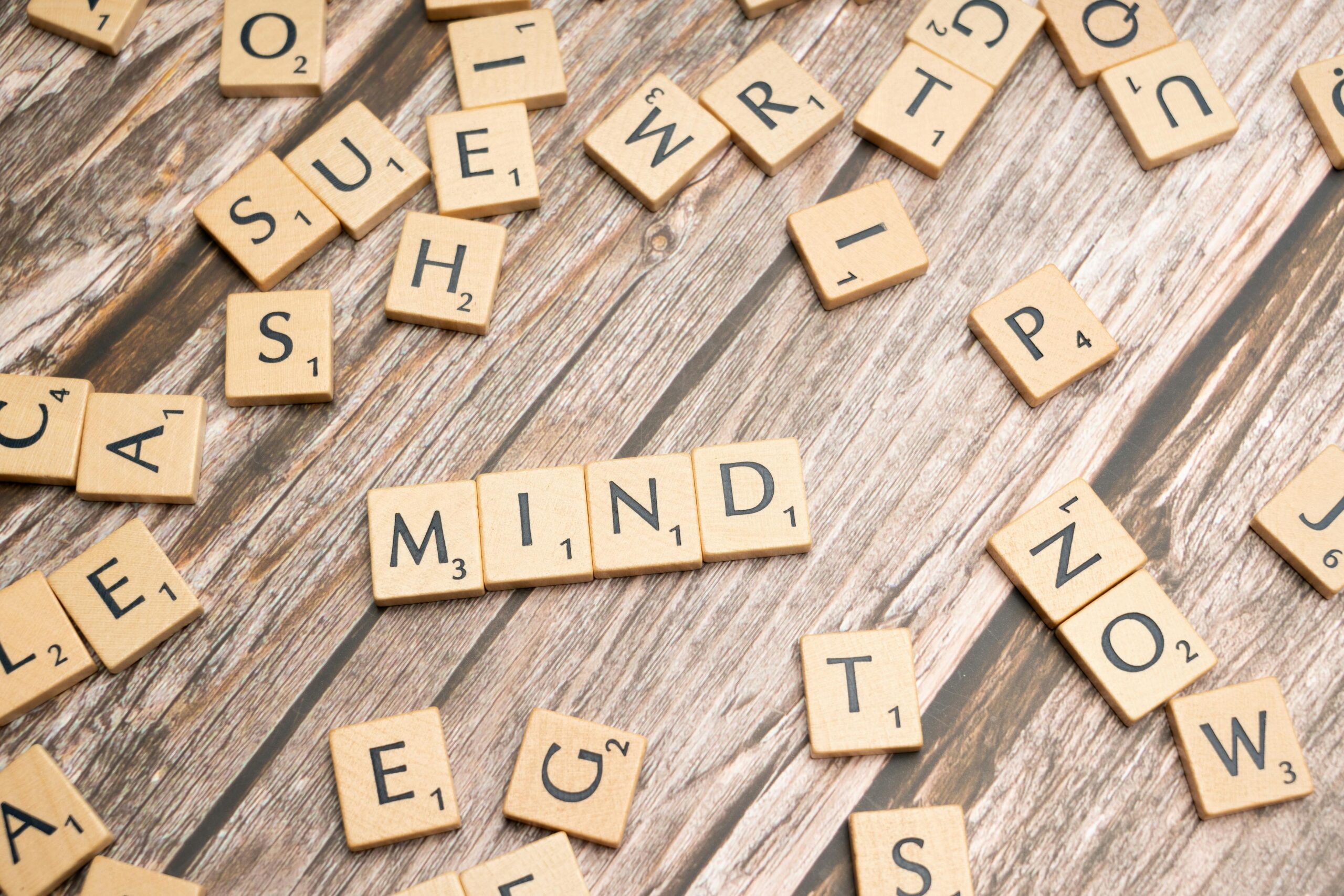 Cognitive Function | Calmly Rooted Scrabble tiles scattered on a wooden surface with the word "MIND" spelled out in the center.