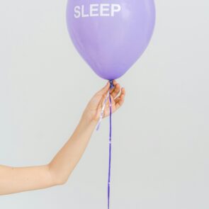 cbd-vs-melatonin-sleep-support-calmly-rooted | Calmly Rooted A hand holding a purple balloon with the word SLEEP for a CBD vs melatonin comparison guide at Calmly Rooted West Bloomfield MI.