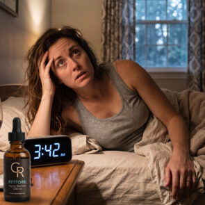 A frustrated woman awake in bed at 3:42 a.m. next to a glass of wine, illustrating how alcohol disrupts sleep, with a bottle of CalmlyRooted wellness drops on the nightstand.