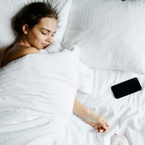 Woman achieving deep sleep recovery with a consistent bedtime ritual, optimized for a high Oura sleep score and HRV at CalmlyRooted.com.