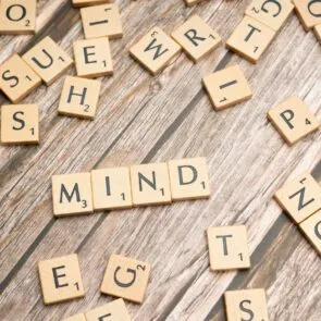 Cognitive Function | Calmly Rooted Scrabble tiles scattered on a wooden surface with the word "MIND" spelled out in the center.