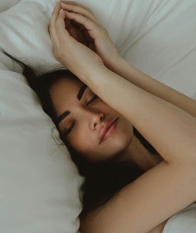 A woman sleeping peacefully on white linens, illustrating the restorative rest benefits of Magnesium Glycinate for sleep.